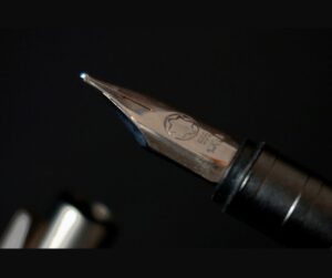 Close-up of a fountain pen tip on a dark background, symbolizing persuasive communication, clarity of message, and effective sales storytelling.